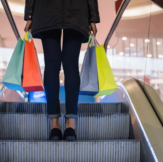 Woman holding some bags and standing on an escalator