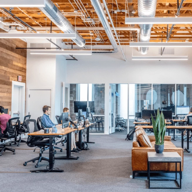 Photo of an office with desks and people working on computers