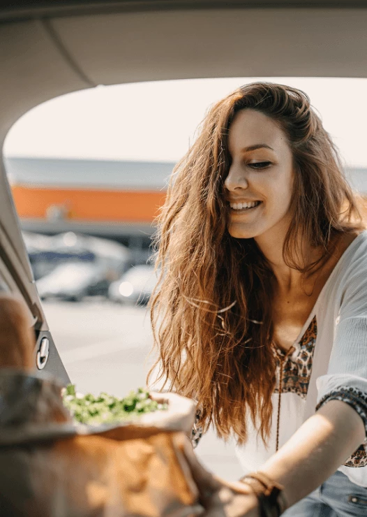 Woman putting a bag of groceries in her car